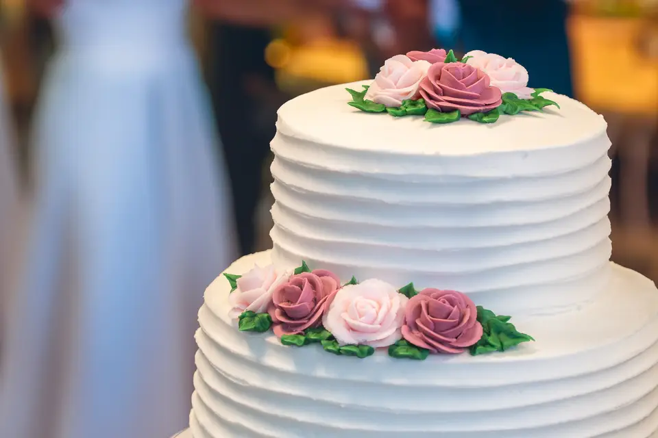 Three-tier white wedding cake with pillars and draped buttercream details by Taylor's Bakery