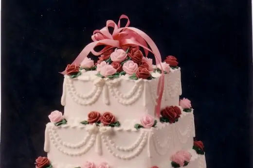 Three-tier white wedding cake with garland piping and pastel buttercream flowers by Taylor's Bakery