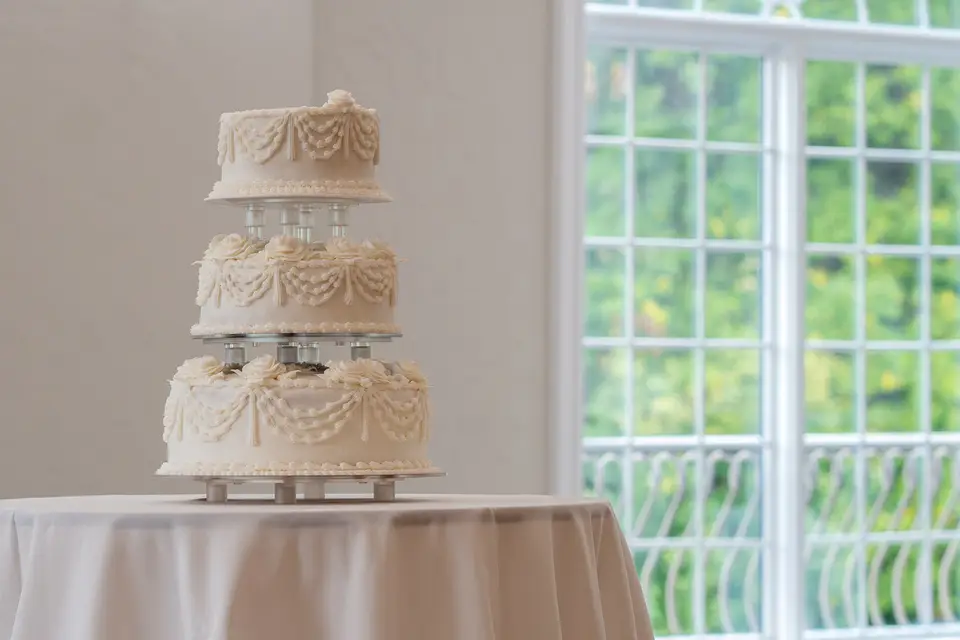 Tiered wedding cake with bright cascading buttercream flowers designed by Taylor's Bakery