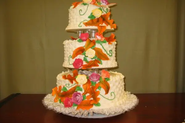 Multi-tier wedding cake with rich floral accents staged in a ballroom by Taylor's Bakery